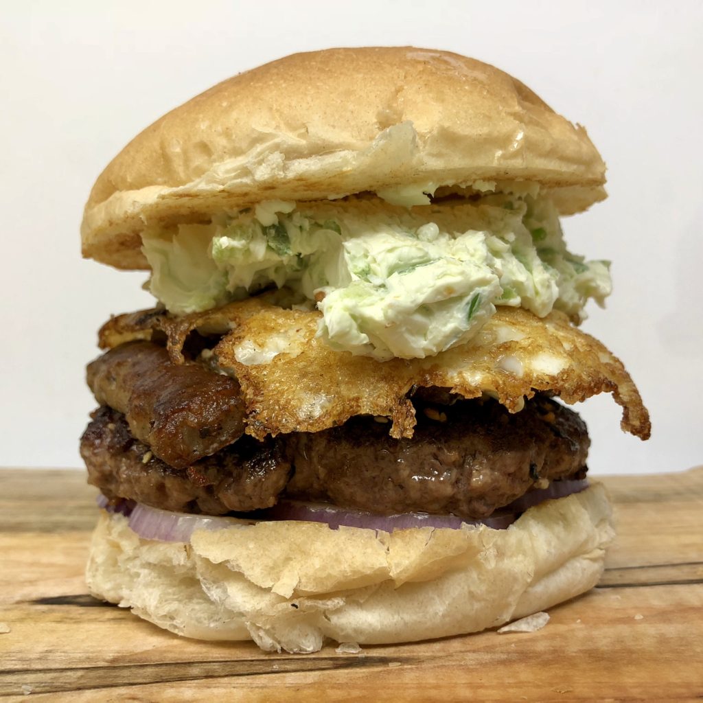 Everything Bagel Burger Fresh ground hand packed angus beef crusted with “everything bagel” spices and topped with an over easy egg, breakfast sausage, a crispy hash brown patty, red onion, and jalapeno-roasted garlic cream cheese