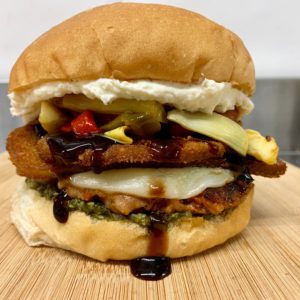 Feast of St. Spicy Sandwich Hot Italian sausage patty topped with provolone, crispy breaded eggplant, sautéed onions, roasted peppers, artichokes, ricotta, basil pesto, and a sweet balsamic reduction