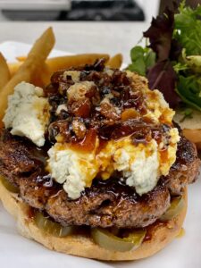King Creole Burger: Half pound of fresh ground hand packed creole spiced beef topped with gorgonzola, hot cherry peppers, bacon jam, and mixed field greens