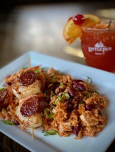 Little Pub Jambalaya Shrimp and Andouille Sausage skewers over a pile of Creole style “dirty rice” loaded with chicken and red beans