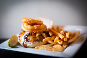 CheddaStacker Burger Half pound of hand packed angus beef topped with melting cheddar, smoked bacon, beer battered onion rings, chipotle- honey bbq sauce and cool buttermilk ranch dressing